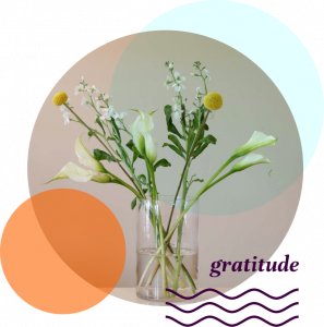 Glass vase with white and yellow flowers. Gratitude and a graphic of wavy lines are in the lower right corner.