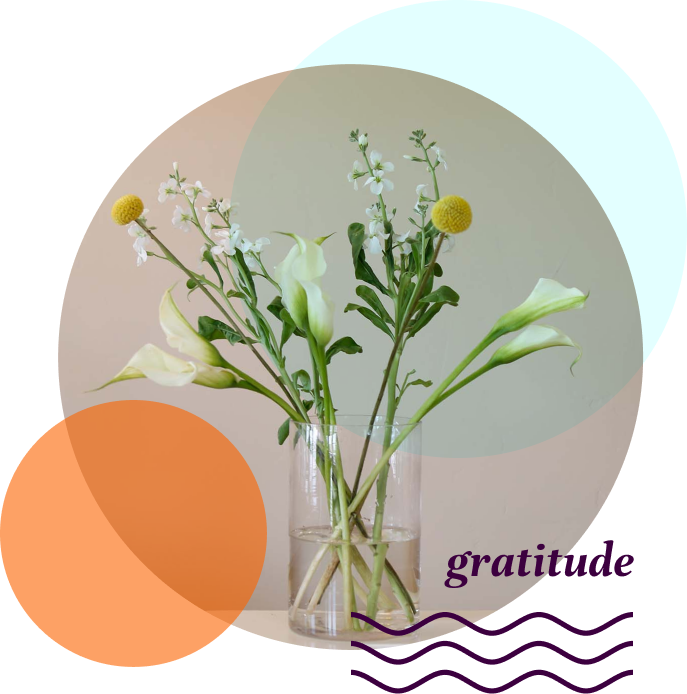 Glass vase with white and yellow flowers. Gratitude and a graphic of wavy lines are in the lower right corner.